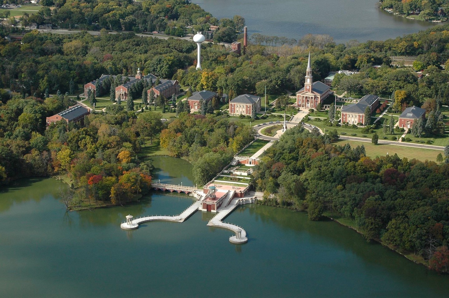 Aerial view of school campus amongst greenery and water.
